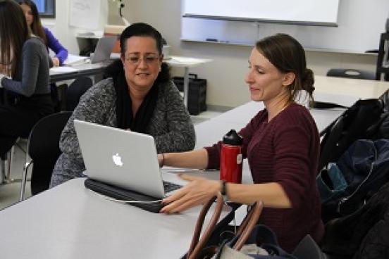 Teacher working with student on laptop