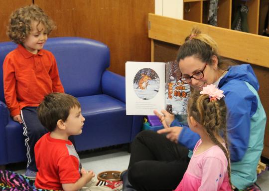 Student reading to three children in a circle